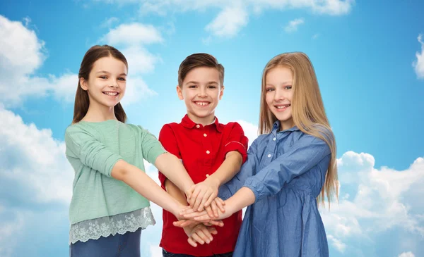 Niños felices con manos en la parte superior sobre el cielo azul —  Fotos de Stock