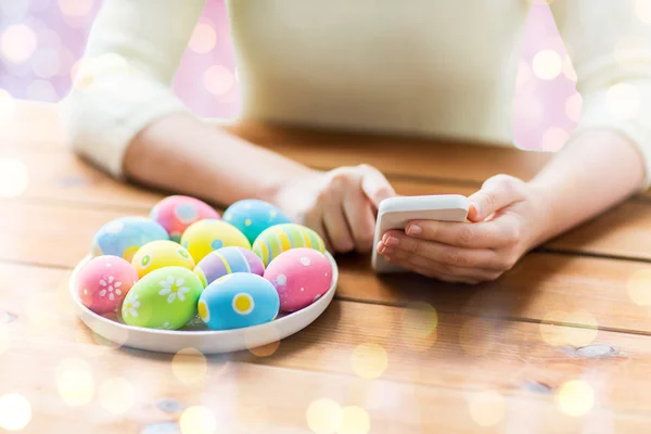 Close up of hands with easter eggs and smartphone — Stock Photo, Image