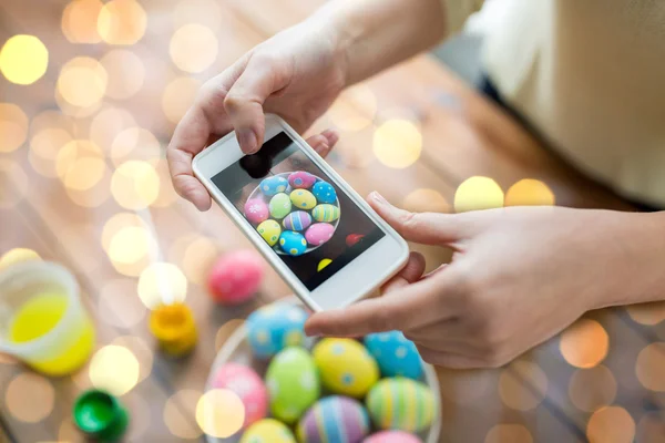 Close up of hands with easter eggs and smartphone — Stock Photo, Image