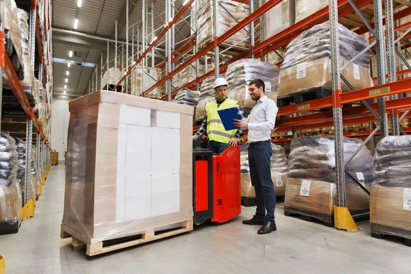 Werknemer op de heftruck en zakenman in magazijn — Stockfoto