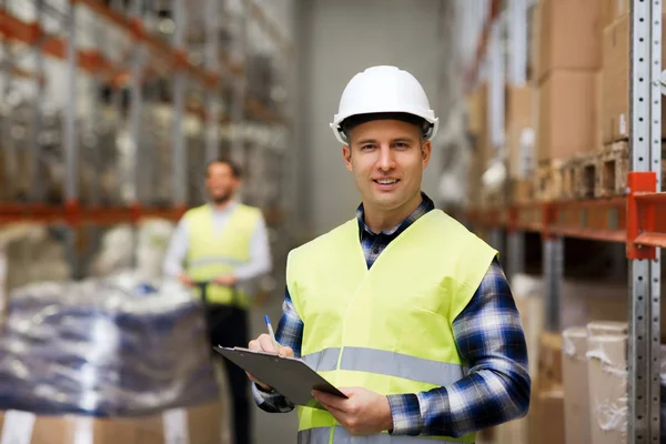 Man with clipboard in safety vest at warehouse — Stock Photo, Image