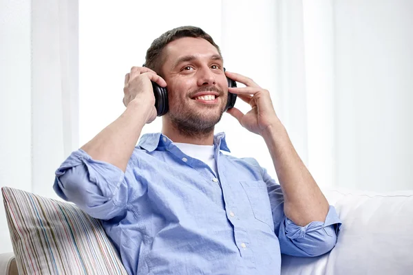 Joven sonriente con auriculares en casa — Foto de Stock