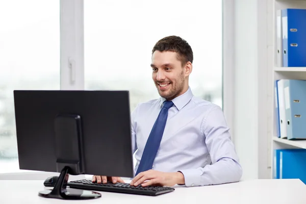 Smiling young businessman with computer at office — Stock Photo, Image