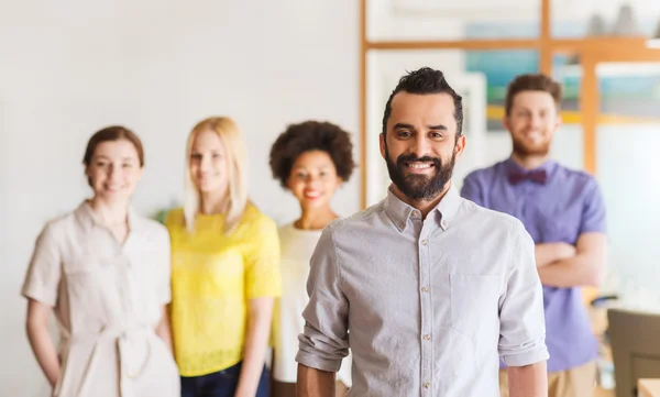 Gelukkig jonge man over creatieve team in office — Stockfoto