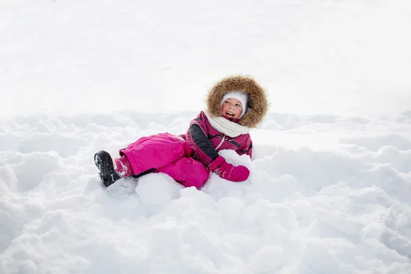 Happy little kid or girl in winter clothes on snow — Stock Photo, Image