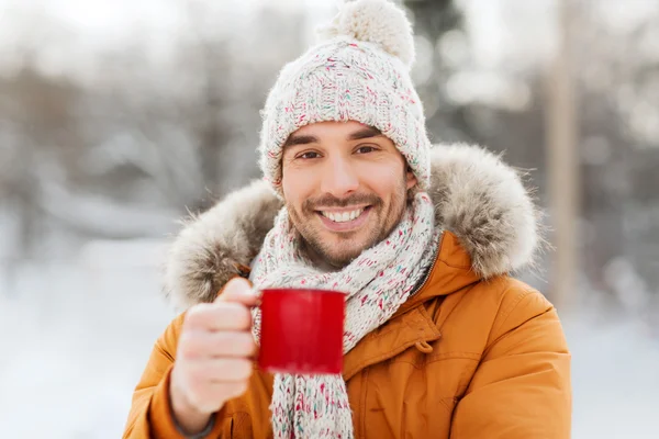 Счастливый человек с чашкой чая на улице зимой — стоковое фото