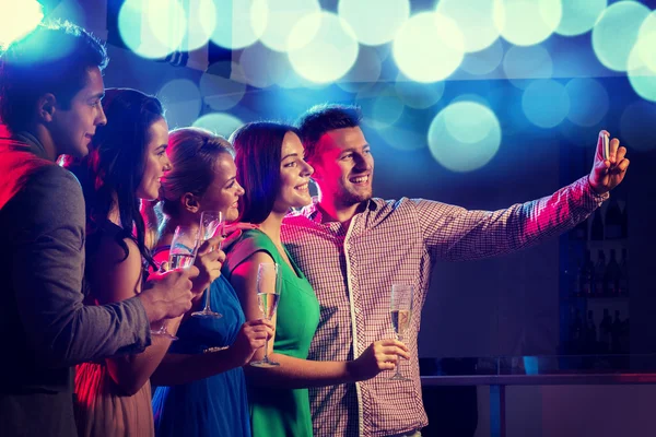 Vrienden met glazen en smartphone in club — Stockfoto