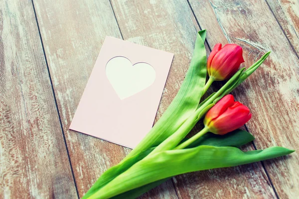 Primer plano de tulipanes y tarjeta de felicitación con corazón — Foto de Stock