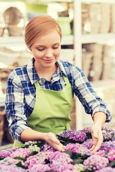 Lycklig kvinna ta hand om blommor i växthus — Stockfoto