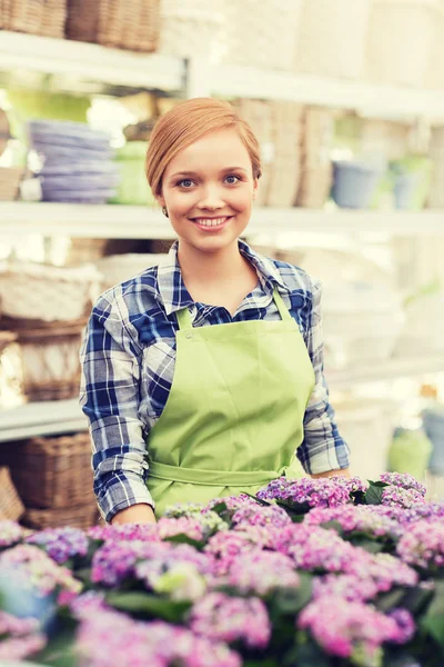Happy woman with flowers in greenhouse — Stock Photo, Image