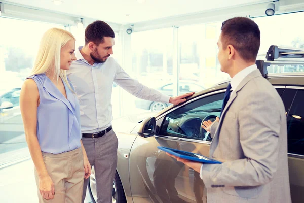 Feliz pareja con concesionario de coches en auto show o salón —  Fotos de Stock