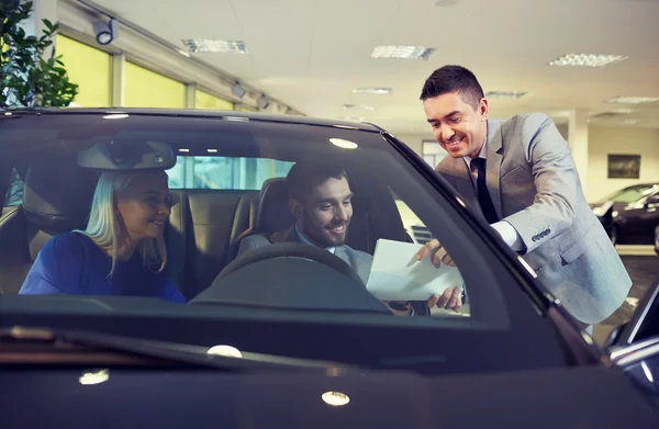 Šťastný pár s prodejci aut v autosalonu nebo salónek — Stock fotografie