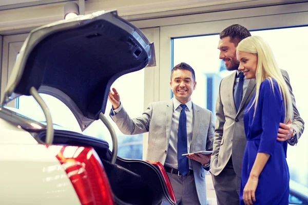 Happy couple with car dealer in auto show or salon — Stock Photo, Image