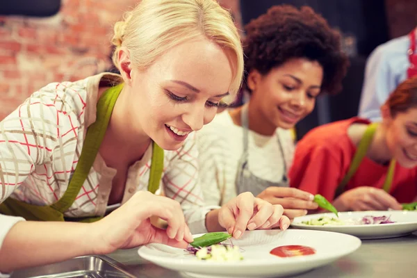 Happy women cooking and decorating dishes — Stock Photo, Image