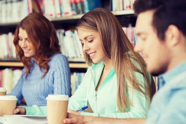 Students reading and drinking coffee in library — Stock Photo, Image