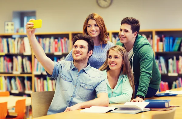 Estudantes com smartphone tirando selfie na biblioteca — Fotografia de Stock