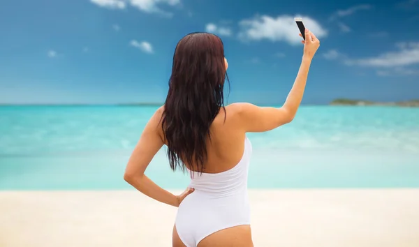 Młoda kobieta robi selfie ze smartfonem na plaży — Zdjęcie stockowe
