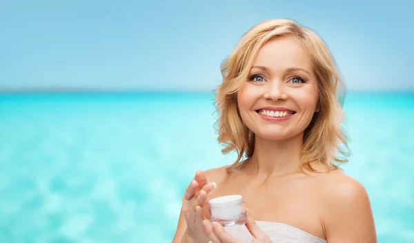 Happy middle aged woman with cream jar over sea — Φωτογραφία Αρχείου