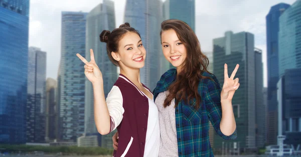 Happy teenage girls hugging and showing peace sign — Stock Photo, Image