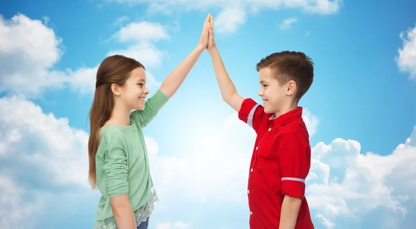 Feliz chico y chica haciendo alto cinco sobre el cielo azul —  Fotos de Stock