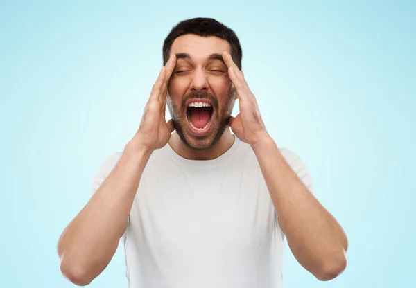 Crazy shouting man in t-shirt over blue background — ストック写真