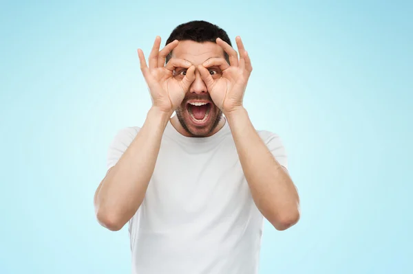 Uomo facendo occhiali dito su sfondo blu — Foto Stock