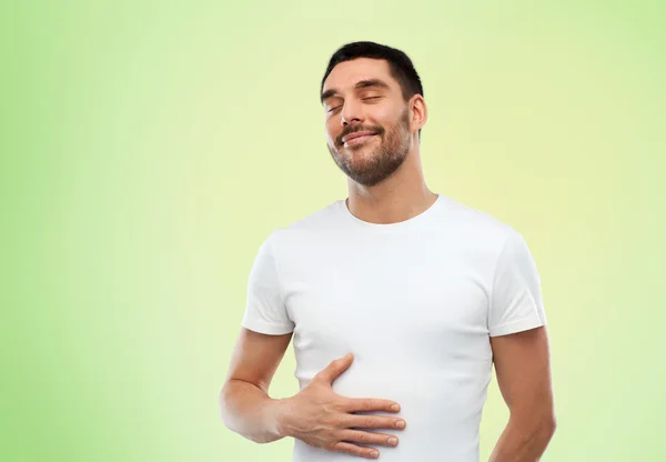 Happy full man touching tummy over green — Stock Fotó