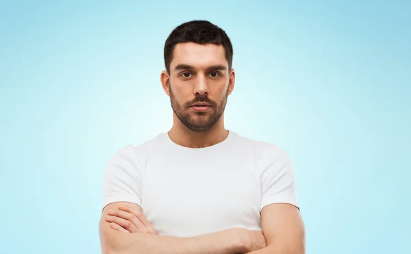 Young man with crossed arms over blue background — Stok fotoğraf