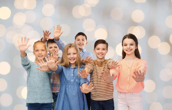 Happy children waving hands over holidays lights — 图库照片