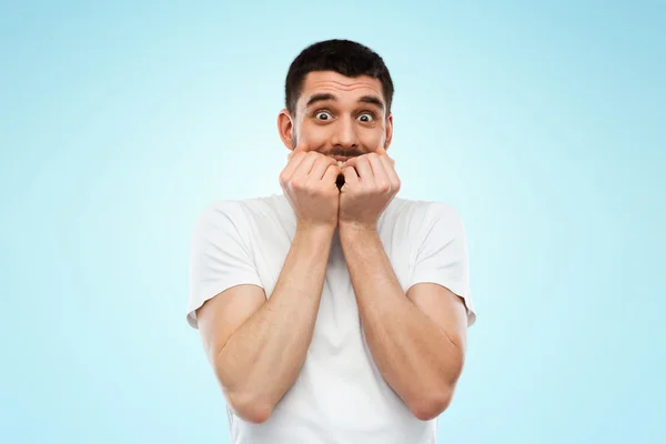 Hombre asustado en camiseta blanca sobre fondo azul — Foto de Stock