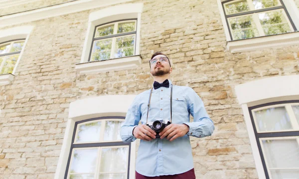 Feliz jovem hipster homem com câmera de filme na cidade — Fotografia de Stock