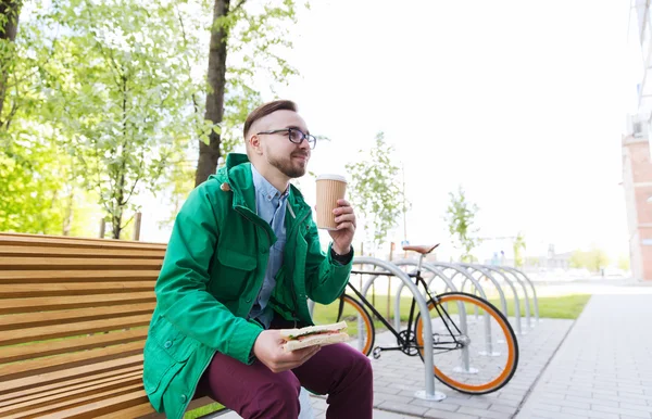 Glücklicher Hipster-Mann isst Sandwich mit Kaffee — Stockfoto