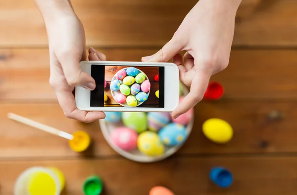 Perto de mãos com ovos de Páscoa e smartphone — Fotografia de Stock