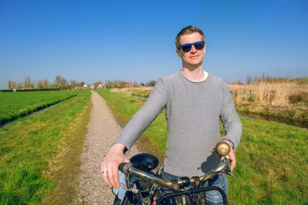 Hombre sosteniendo bicicleta en el campo — Foto de Stock