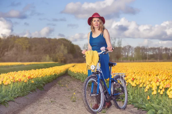 Mujer alegre caminando con su bicicleta por el campo — Foto de Stock