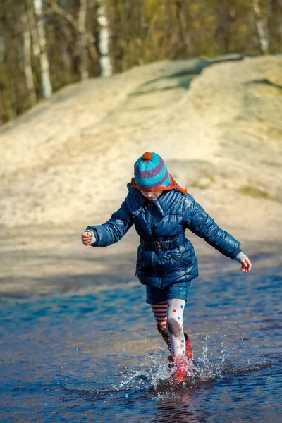 Tjej springa och hoppa i pöl — Stockfoto