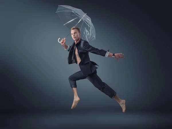 Knappe manager springen met een paraplu — Stockfoto