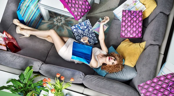 Satisfied young lady lying among many shopping bags — Stock Photo, Image