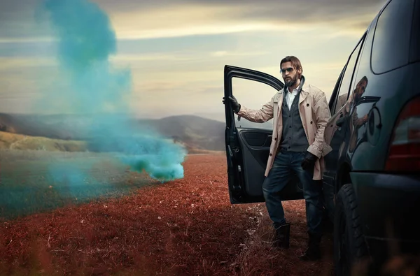 Hombre guapo y elegante en la carretera junto a su coche Imágenes de stock libres de derechos