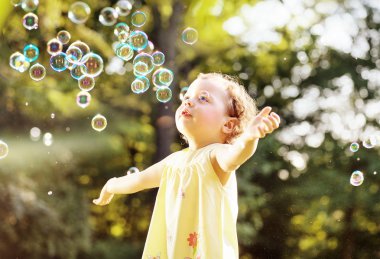 Küçük kız bir yaz çayır sabun köpüğü üfleme