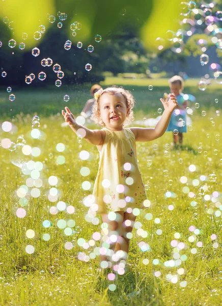 Портрет двох маленьких дівчат, які грають разом мильні бульбашки — стокове фото
