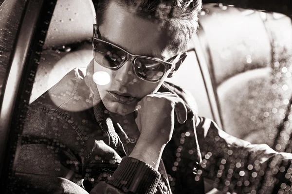 Retrato en blanco y negro de un hombre guapo sentado en el coche — Foto de Stock