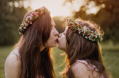 Sevgili kızını öpen güzel bir annenin portresi. Açık hava konsepti.