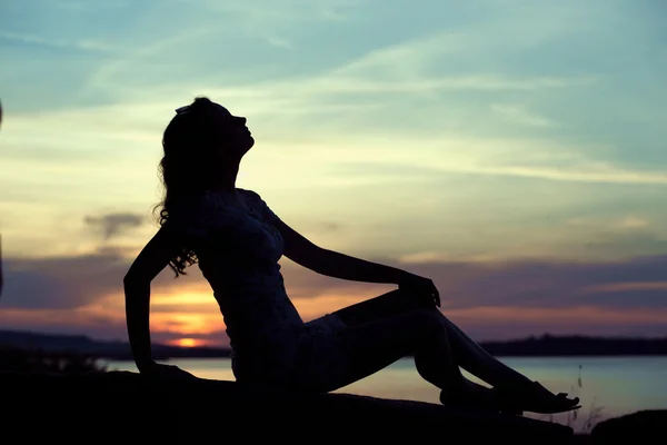 Silhouette der jungen Frau, die am Meer sitzt — Stockfoto
