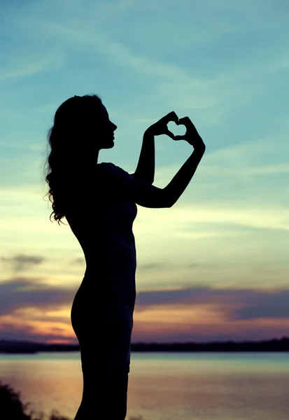 Silhouette of the woman making the heart sign — Stock Photo, Image