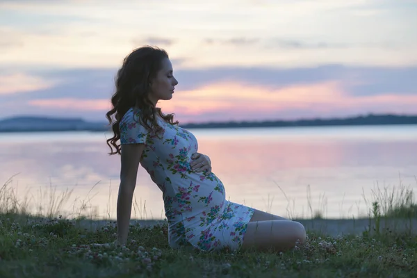 Kalm zwangere vrouw zittend op de oever van het meer Rechtenvrije Stockfoto's