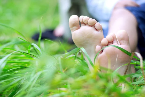 Liten pojke fötter på gräs — Stockfoto