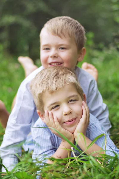 Dois irmãos pequeninos relaxando em uma grama — Fotografia de Stock