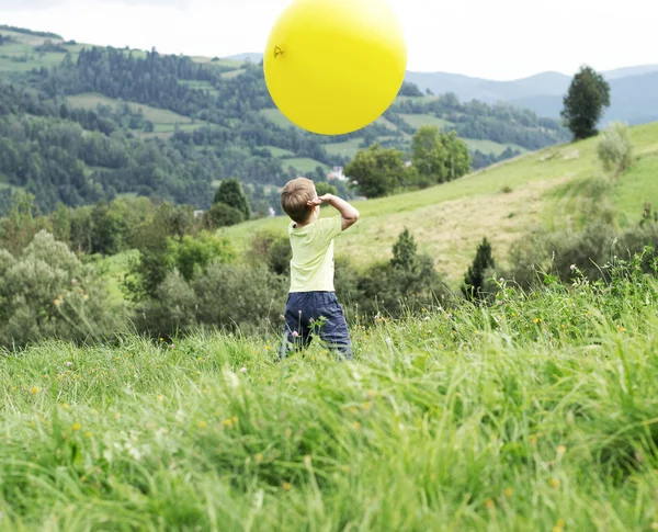 Маленький мальчик играет на огромном шаре — стоковое фото