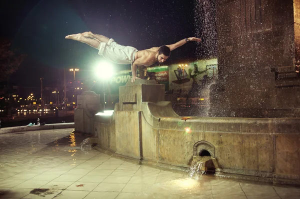 Fit guy doing push-ups in a fountain — Stock Photo, Image